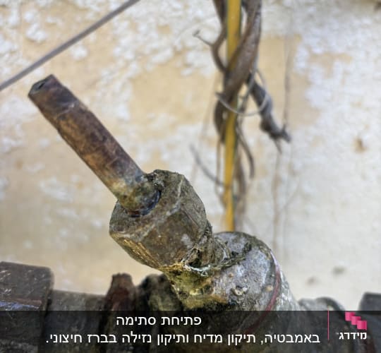 ברז חלוד עם צינור מחובר לקיר